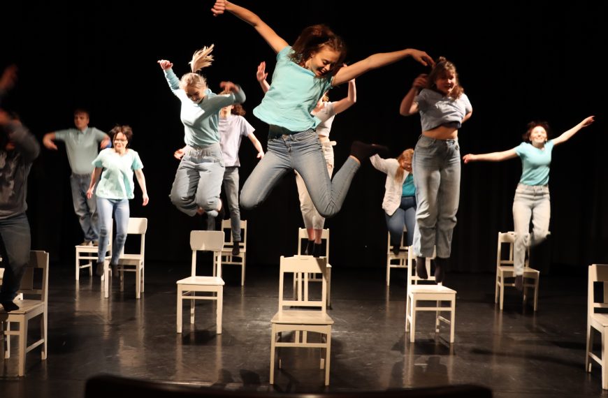 Kuva esityksestä, kun näyttelijät hyppäävät alas tuoleiltaan.